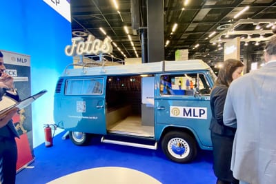 Blau folierter Fotobulli mit MLP-Logo, QR-Code und Claim auf der Seitenwand, komplett in der CI des Ausstellers gebrandet.