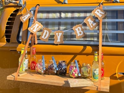 Ausgeklappte Seitenklappe des Bullis mit Süßigkeitengläsern, Getränken und einer „Candy-Bar“-Girlande.